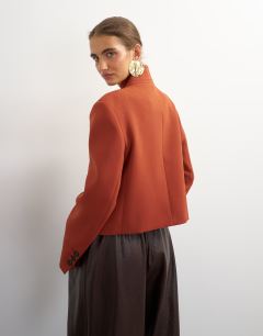 Model wearing Assymetric neck button detail blazer in rust