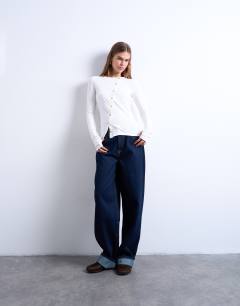 Model wearing Asymmetric button through long sleeve top in ivory