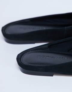 Model wearing Atlas mule flat shoe in black