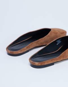 Model wearing Atlas mule flat shoe in tan