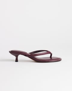 Model wearing Axel toe thong mid heel sandal in aubergine