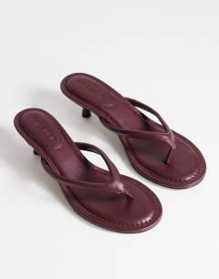 Model wearing Axel toe thong mid heel sandal in aubergine