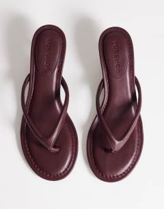 Model wearing Axel toe thong mid heel sandal in aubergine
