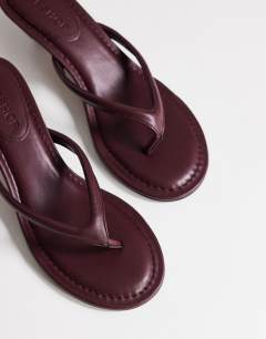 Model wearing Axel toe thong mid heel sandal in aubergine