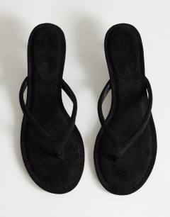 Model wearing Axel toe thong mid heel sandal in black faux suede 
