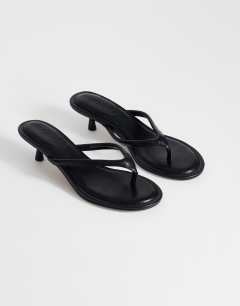 Model wearing Axel toe thong mid heel sandal in black