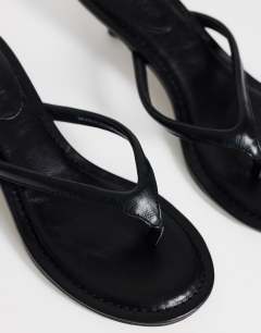 Model wearing Axel toe thong mid heel sandal in black
