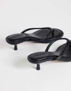Model wearing Axel toe thong mid heel sandal in black