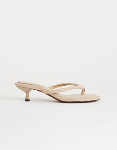 Model wearing Axel toe thong mid heel sandal in camel