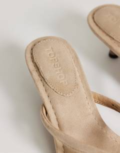 Model wearing Axel toe thong mid heel sandal in camel