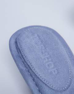 Model wearing Axel toe thong mid heel sandal in cornflower blue