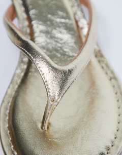 Model wearing Axel toe thong mid heel sandal in gold