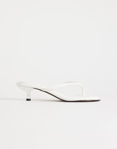 Model wearing Axel toe thong mid heel sandal in white