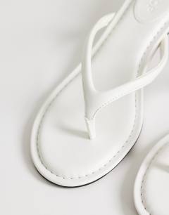 Model wearing Axel toe thong mid heel sandal in white