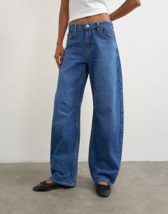 Model wearing Barrel mid rise jean in mid blue