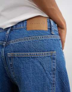 Model wearing Barrel mid rise jean in mid blue
