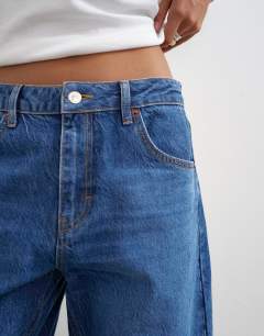 Model wearing Barrel mid rise jean in mid blue