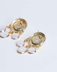 Model wearing Becca drop earrings in gold and pearl