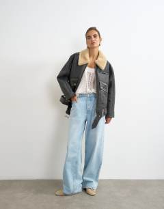 Model wearing Belted faux leather jacket in black and tan