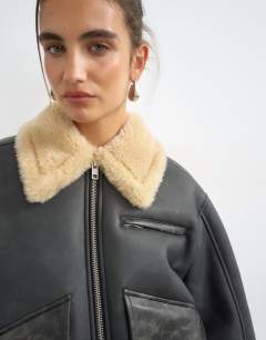Model wearing Belted faux leather jacket in black and tan