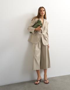Model wearing Belted pleated cropped wide leg trouser in beige