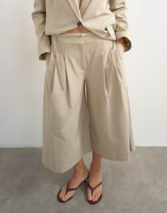 Model wearing Belted pleated cropped wide leg trouser in beige