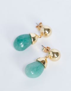 Model wearing Blaze stud earrings with drop design in gold and green