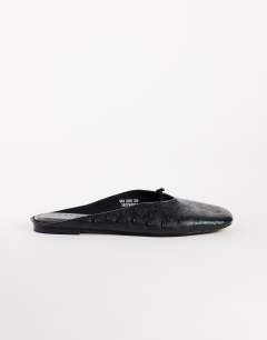 Model wearing Blythe knotted flat mule in black textured