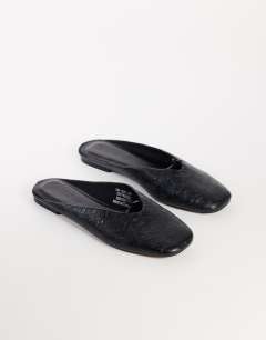 Model wearing Blythe knotted flat mule in black textured
