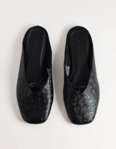 Model wearing Blythe knotted flat mule in black textured
