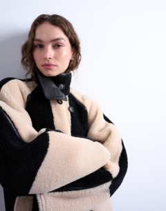 Model wearing Borg longline ovoid sleeve patchwork funnel neck coat in black