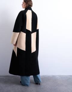 Model wearing Borg longline ovoid sleeve patchwork funnel neck coat in black
