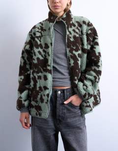 Model wearing Brown and teal cow print borg fleece jacket with contrast teal binding in multi