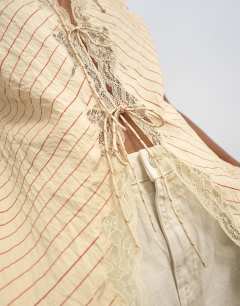 Model wearing Cap sleeve asymmetric tie front lace detail top in yellow stripe 