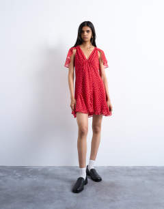 Model wearing Cape sleeve godet hem mini dress in red based spot