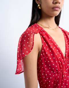 Model wearing Cape sleeve godet hem mini dress in red based spot