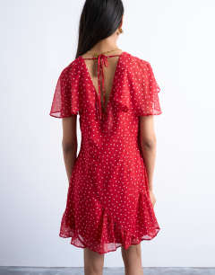 Model wearing Cape sleeve godet hem mini dress in red based spot