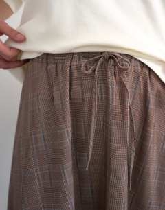 Model wearing Co ord check tie waist pleated maxi skirt in brown