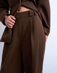 Model wearing Co ord double pleat suit trouser in brown 