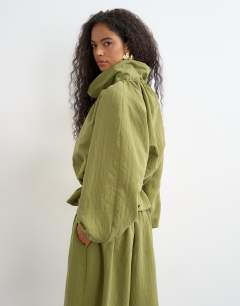 Model wearing Co ord funnel neck jacket with tie waist in olive