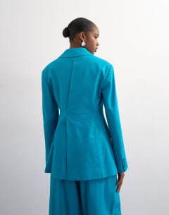 Model wearing Co ord occasion strong shoulder cinched waist blazer in turquoise
