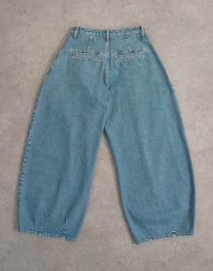 Model wearing Cocoon mid rise barrel jean in green cast - MBLUE