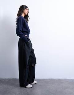 Model wearing Column mid rise jean with rip in washed black