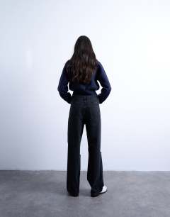 Model wearing Column mid rise jean with rip in washed black