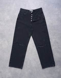 Model wearing Column mid rise jean with rip in washed black