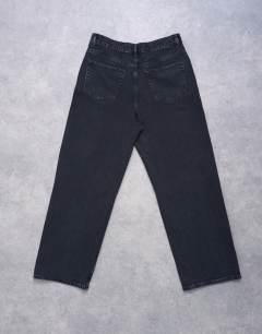 Model wearing Column mid rise jean with rip in washed black