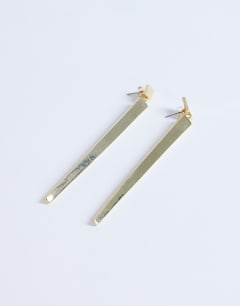 Model wearing Cora asymmetric drop stud earring in gold tone