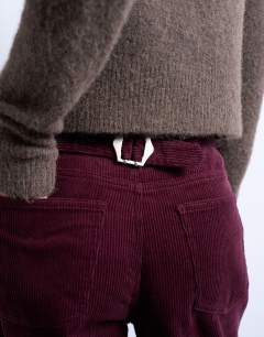 Model wearing Cord slouchy low slung trouser in burgundy