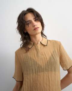 Model wearing Crinkle polo shirt with black tipping in mocha