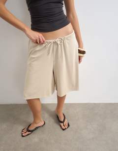 Model wearing Cupro bermuda drawstring shorts in cream